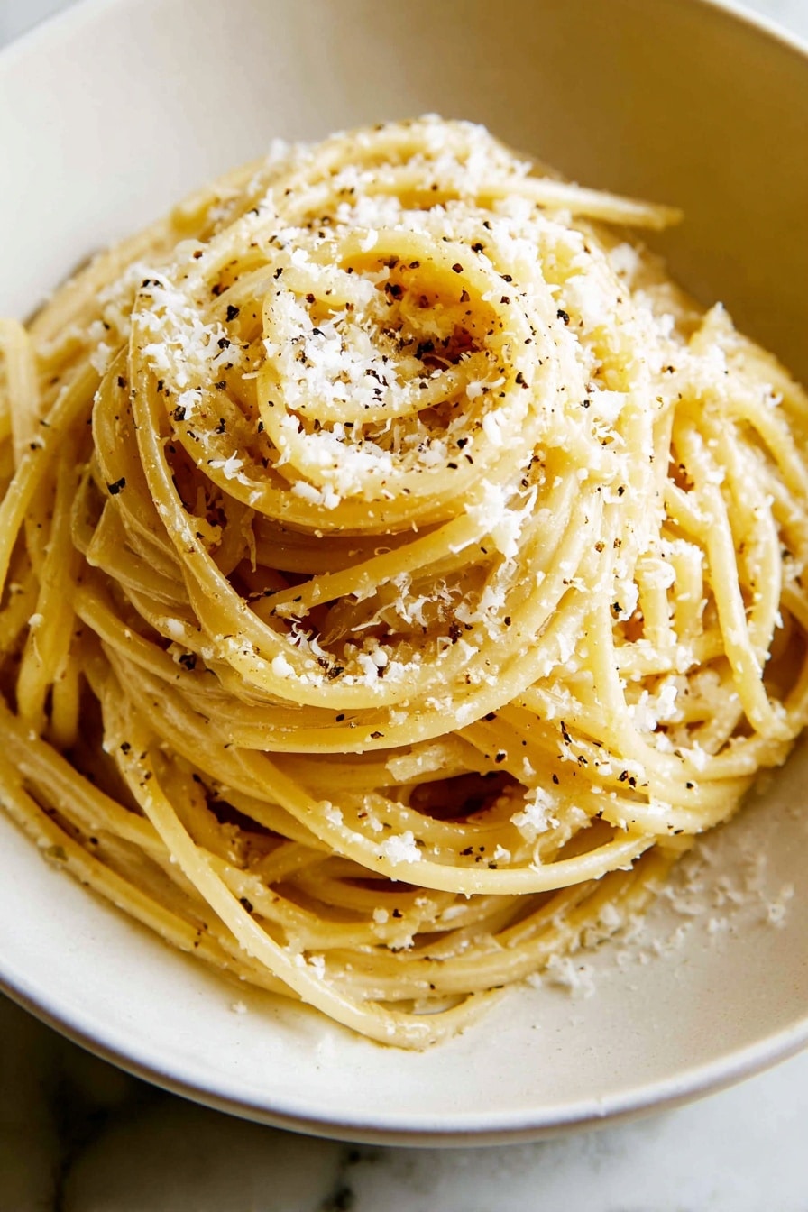 A white bowl holds a mound of spaghetti pasta coated in a light yellow sauce, speckled with small black pepper bits, with finely grated white cheese sprinkled over the top layer. A fork lifts a bundle of the pasta above the bowl, showing the smooth texture and twist of the noodles. In the background, there is a small white bowl with more grated cheese. The scene is set on a white marbled surface. photo taken with an iphone --ar 2:3 --v 7 - Creamy Cacio e Pepe Pasta, Cacio e Pepe pasta recipe, how to make creamy cacio e pepe, easy cacio e pepe pasta, quick Italian pasta dish