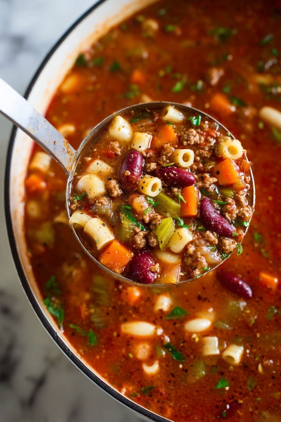 A close-up view of a ladle holding a rich, chunky soup above a white pot with a black rim, all resting on a white marbled surface. The soup has multiple layers visible: a thick, deep red broth base mixed with small bits of brown ground meat, bright orange carrot cubes, pale white and red kidney beans, green celery slices, and small round pasta pieces. Fresh green herbs are sprinkled throughout, adding a fresh touch. Black pepper flecks are visible on the surface of the soup and ladle, giving it a seasoned look. photo taken with an iphone --ar 2:3 --v 7 - Pasta e Fagioli Soup Olive Garden, Italian Copycat Soup, Hearty Bean and Pasta Soup, Easy Olive Garden Copycat Recipe, Comfort Food Soup Recipes