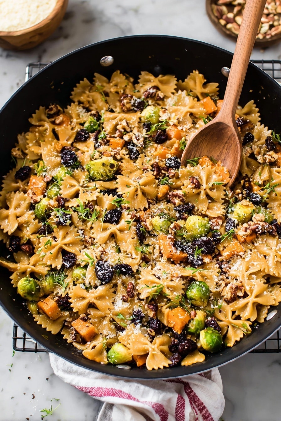 A large black pot filled with a colorful mix of farfalle pasta and small pieces of roasted orange sweet potatoes spread all over. Bright green Brussels sprouts cut in halves and small dark purple dried berries are scattered inside. There are bits of chopped pecans and a light sprinkle of grated cheese on top, with little green herb leaves spread around. In the pot, a wooden spoon rests on the food, and the scene is set on a white marbled surface, with some pecans and a small bowl of grated cheese nearby. A white cloth with a red stripe is partially visible next to the pot. Photo taken with an iphone --ar 2:3 --v 7 - Brussels Sprouts Pasta with Brown Butter, Brussels Sprouts Pasta, brown butter pasta, healthy Brussels sprouts recipes, cozy vegetarian pasta