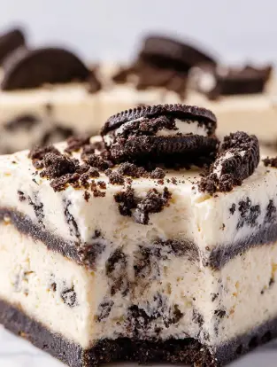 This image shows a close-up of a square dessert made of four thick layers. The base layer is creamy white with bits of dark brown cookie mixed inside. Above this is a thin, even layer of dark brown cookie pieces. The next layer is another thick creamy white layer with small cookie bits scattered throughout. The top layer is a smooth cream color studded with large crumbled pieces of dark brown cookie, some sitting on the surface. The dessert sits on a white marbled surface, and one edge shows a bite taken out. The texture looks soft and slightly firm. Photo taken with an iphone --ar 2:3 --v 7 - White Chocolate Oreo Fudge, easy Oreo fudge recipe, no-bake Oreo dessert, quick white chocolate fudge, simple Oreo fudge