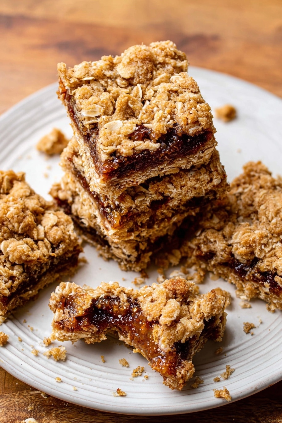 The image shows four oat bars stacked slightly on each other on a white plate with a textured edge. Each oat bar has two visible layers: the top and bottom layers are golden brown with a crumbly texture mixed with oat flakes, and the middle layer is a dark brown fig filling with visible seeds and a sticky look. One oat bar on the plate is broken in half, revealing the thick filling inside. There are crumbs scattered on the plate and around it on a wooden surface. Photo taken with an iphone --ar 2:3 --v 7 - Homemade Oatmeal Fig Bars, healthy oatmeal fig bars, homemade fig bar recipe, wholesome fig bars, easy fig bar recipe