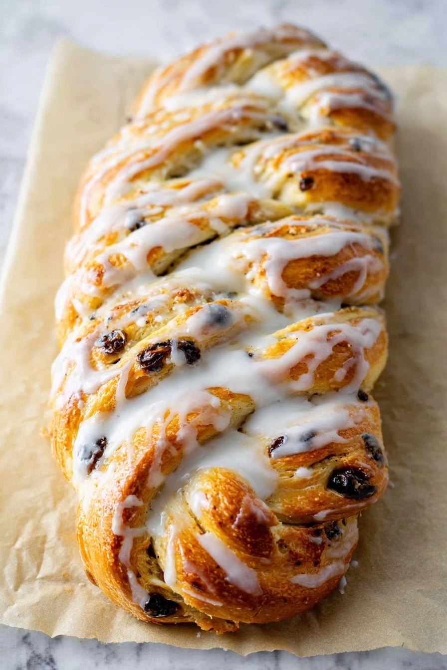A golden brown braided bread loaf is placed on a sheet of parchment paper on a white marbled surface. The bread has multiple visible layers formed by the braid, with bits of dark raisins or chocolate chips scattered throughout the dough. A thick, white glaze is drizzled generously and unevenly over the top, pooling slightly in the crevices and along the edges, giving it a shiny, slightly wet look. The texture of the bread appears soft and fluffy with a slightly crisp crust on top. Photo taken with an iphone --ar 2:3 --v 7 - German Stollen Bread, holiday bread, traditional German stollen, fruit and nut bread, festive Christmas bread