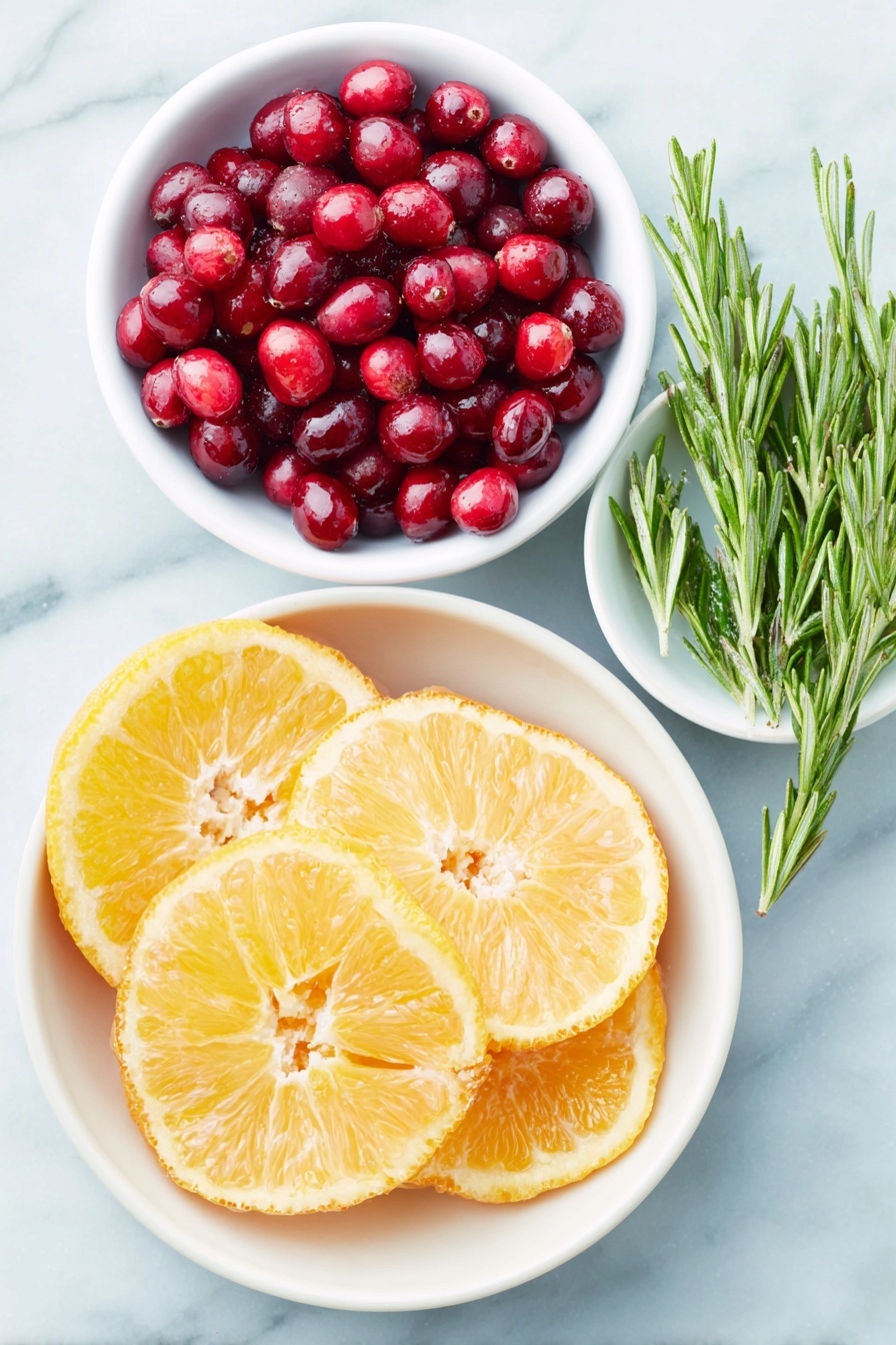 Flat lay of fresh orange slices arranged in a simple white ceramic bowl, a small white bowl filled with bright red cranberries, a small white bowl holding glossy pomegranate seeds, fresh rosemary sprigs laid neatly beside the bowls, all placed on a clean white marble surface, soft natural light, photo taken with an iPhone, professional food photography style, fresh ingredients, white ceramic bowls, no bottles, no duplicates, no utensils, no packaging --ar 2:3 --v 7 --p m7354615311229779997 - Festive Cranberry Orange Punch, Cranberry Orange Punch Ingredients, Holiday Fruit Punch, Alcohol-Free Party Punch, Winter Cocktail Ideas