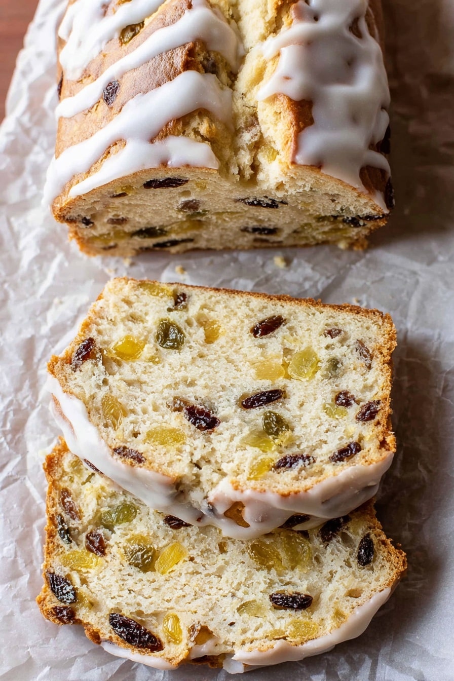 The image shows a loaf of sweet bread with a golden-brown top covered with white icing drizzled over it. The bread is sliced into three pieces, revealing a soft, light beige inside filled with bits of dark raisins and light yellow fruit pieces evenly spread throughout. The bread sits on crumpled parchment paper placed on a white marbled surface, and the slices have a slightly rough texture with visible fruit chunks inside. The crust looks thin and slightly shiny beneath the icing. Photo taken with an iphone --ar 2:3 --v 7 - German Stollen Bread, holiday bread, traditional German stollen, fruit and nut bread, festive Christmas bread