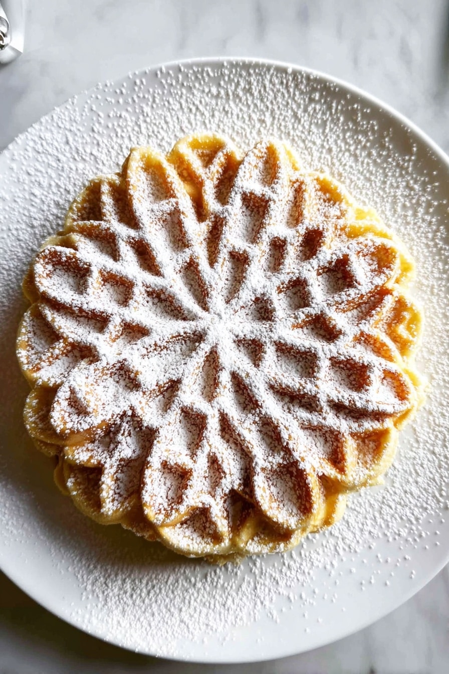 A round waffle with eight clear, deep petals arranged in a floral pattern covers the top surface, with textured edges around the circle. The waffle is light golden brown with slightly darker highlights in the deeper sections of the pattern. It is sprinkled generously with white powdered sugar that lightly dusts the waffle and the white plate beneath it, sitting on a white marbled surface. Photo taken with an iphone --ar 2:3 --v 7 - Easy Italian Pizzelle Cookies, pizzelle cookies recipe, authentic Italian pizzelle, how to make pizzelle cookies, Italian cookie recipes