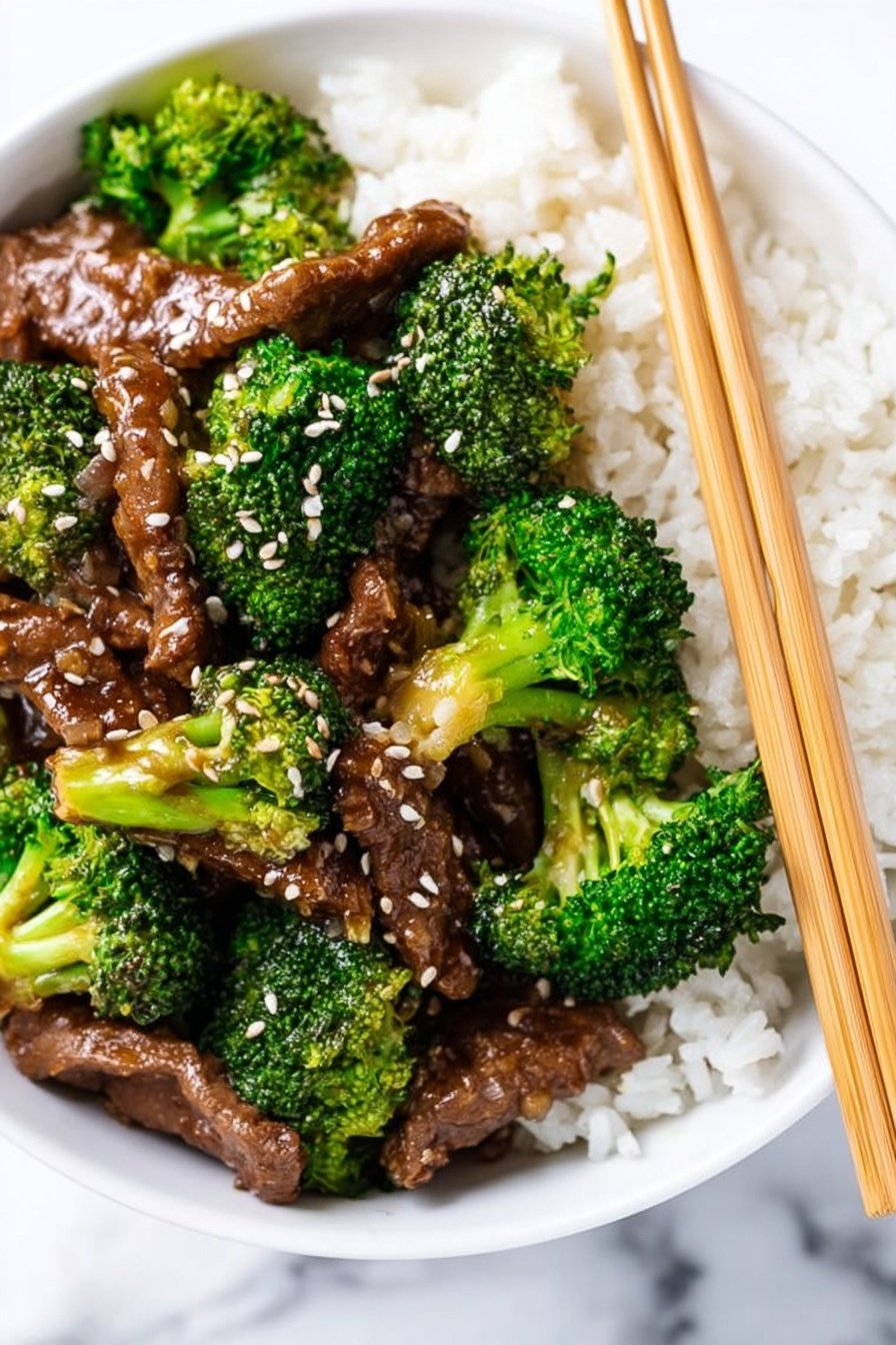 A white bowl filled with a bed of white rice as the bottom layer, topped with bright green broccoli florets and brown cooked meat strips covered in a glossy sauce. The meat and broccoli pieces are sprinkled with white sesame seeds. Two light brown chopsticks are resting on the right side of the bowl. The bowl sits on a white marbled surface. photo taken with an iphone --ar 2:3 --v 7 - Crockpot Beef and Broccoli, Crockpot beef and broccoli recipe, slow cooker beef and broccoli, easy Chinese Beef and Broccoli, healthy beef stir-fry