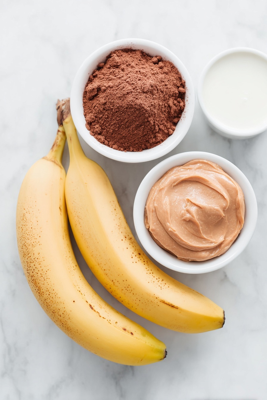 Flat lay of two large ripe yellow bananas with some brown speckles, a small white ceramic bowl filled with fine dark brown cocoa powder, a small white ceramic bowl containing smooth light brown peanut butter, and a small white ceramic bowl holding creamy off-white dairy-free milk, all arranged in perfect symmetry, placed on a clean white marble surface, soft natural light, photo taken with an iPhone, professional food photography style, fresh ingredients, white ceramic bowls, no bottles, no duplicates, no utensils, no packaging --ar 2:3 --v 7 --p m7354615311229779997 - Chocolate Banana Smoothie Bowl, healthy smoothie bowl recipes, quick breakfast ideas, indulgent yet healthy breakfast, banana smoothie bowl
