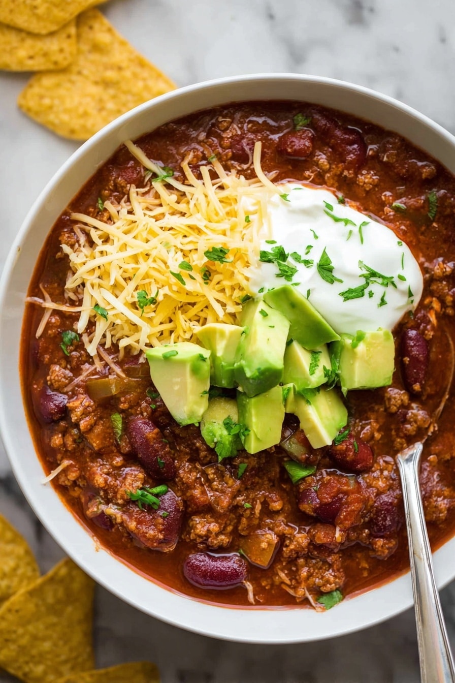 A close-up view of a pot filled with thick chili. The dish has layers of dark brown ground meat mixed with red kidney beans and pieces of diced red peppers. A wooden spoon is stirring the chili on the right side, showing the dense, rich texture of the sauce with visible small chunks of ingredients. The background is a white marbled texture. Photo taken with an iphone --ar 2:3 --v 7 - Slow Cooker Beef Chili, hearty beef chili, easy slow cooker chili, flavor-packed beef stew, comforting chili recipe