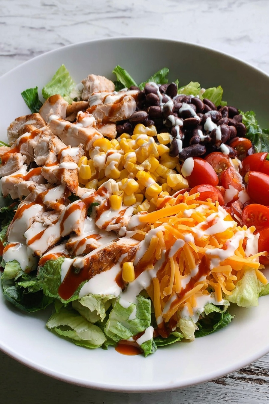 The image shows a white plate filled with a layered salad. The bottom layer consists of green leafy lettuce spread across the plate. Pieces of cooked chicken with light golden-brown edges are placed on the left side. Next to the chicken are bright yellow corn kernels, followed by halved cherry tomatoes at the front. On the right side are black beans, and next to them is shredded orange cheddar cheese. The whole salad is drizzled with white creamy dressing and a reddish-brown sauce in thin lines. The plate sits on a white marbled textured surface. Photo taken with an iphone --ar 2:3 --v 7 - BBQ Ranch Chicken Cobb Salad, Chicken Cobb Salad with BBQ and Ranch, Easy BBQ Chicken Salad, Chicken Salad recipes, Quick Dinner Salads