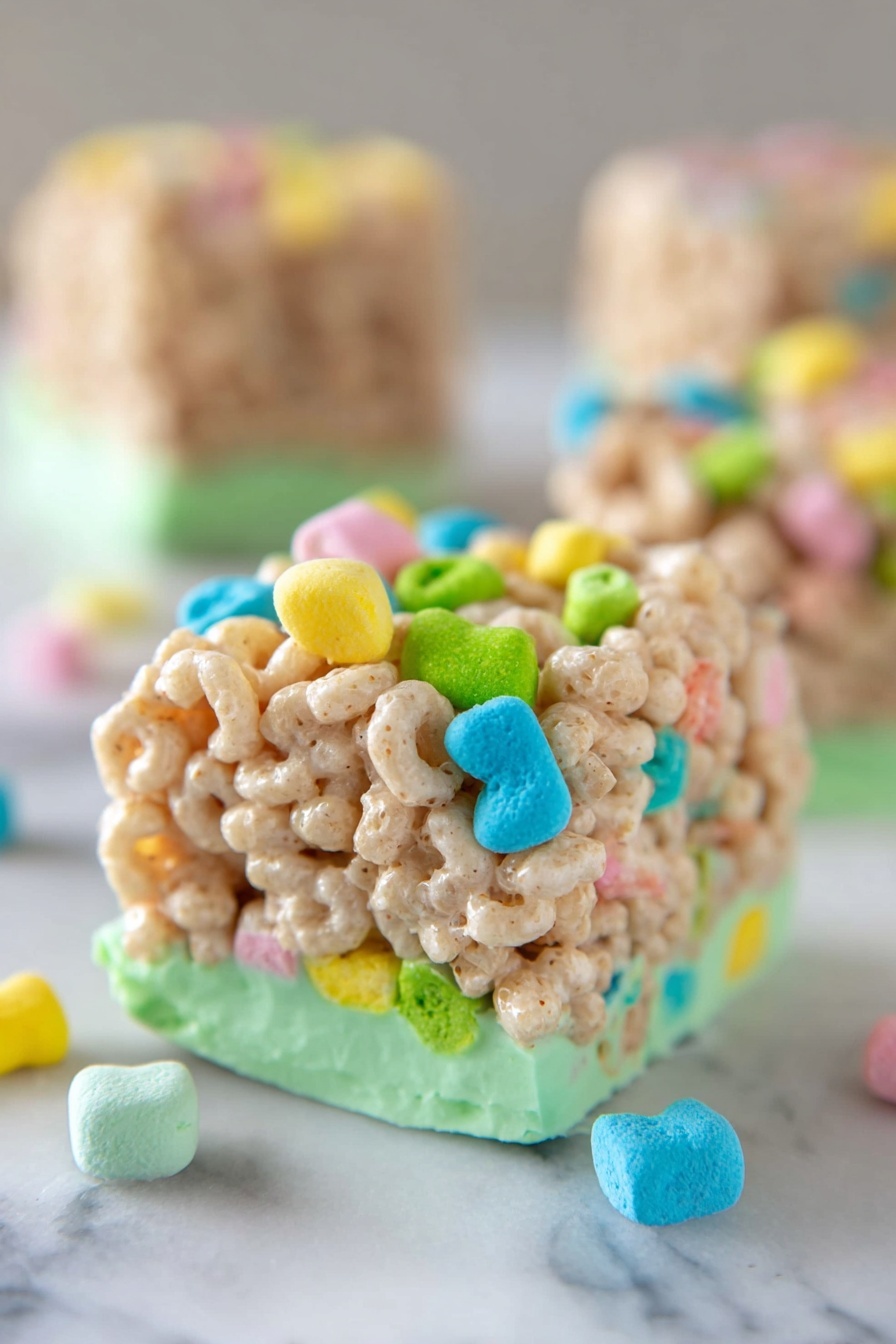 The image shows a close-up of a square-shaped sweet treat made of light beige puffed cereal pieces mixed with colorful, small, marshmallow shapes in bright colors like green, yellow, blue, pink, and orange. The bottom layer is coated with a smooth, light green frosting that supports the cereal cube. The block is sitting on a white marbled surface with a few loose, colorful marshmallows scattered nearby. The background is softly blurred with another similar cereal cube visible. Photo taken with an iphone --ar 2:3 --v 7 - Lucky Charms Cereal Bars, colorful cereal bar recipe, easy marshmallow cereal bars, kid-friendly dessert ideas, nostalgic breakfast treats