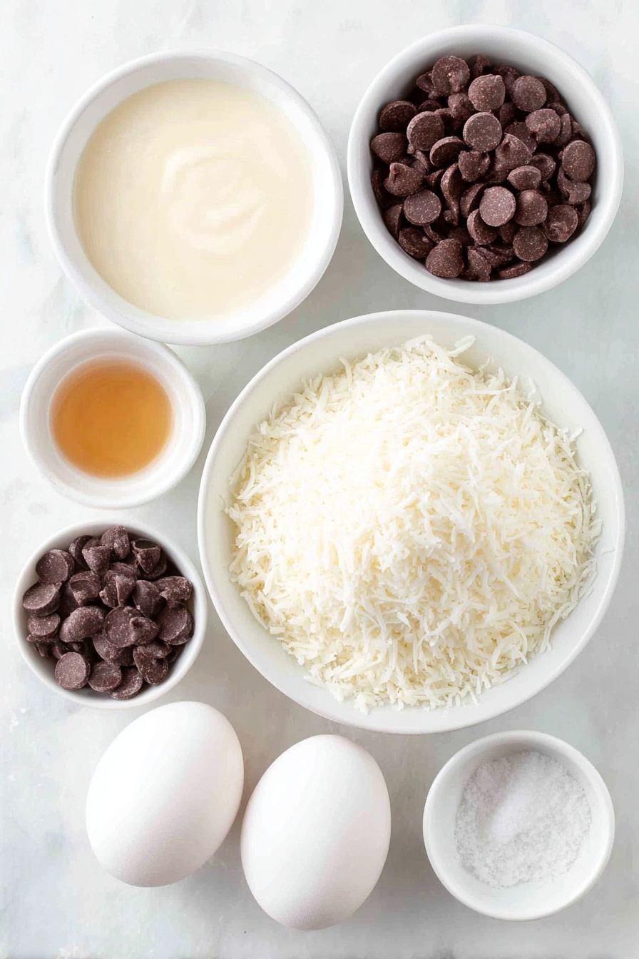 Flat lay of a small mound of fresh sweetened shredded coconut, a small white bowl filled with thick sweetened condensed milk, a few drops of golden vanilla extract in a tiny white bowl, a pinch of coarse salt in another small white bowl, two large whole white eggs with clean shells, and a small white bowl of glossy semi-sweet chocolate chips, all arranged in perfect symmetry on a clean white marble surface, soft natural light, photo taken with an iPhone, professional food photography style, fresh ingredients, white ceramic bowls, no bottles, no duplicates, no utensils, no packaging --ar 2:3 --v 7 --p m7354615311229779997 - Delicious Coconut Macaroons with Chocolate, coconut macaroons, chocolate-covered macaroons, easy coconut treats, chewy coconut cookies