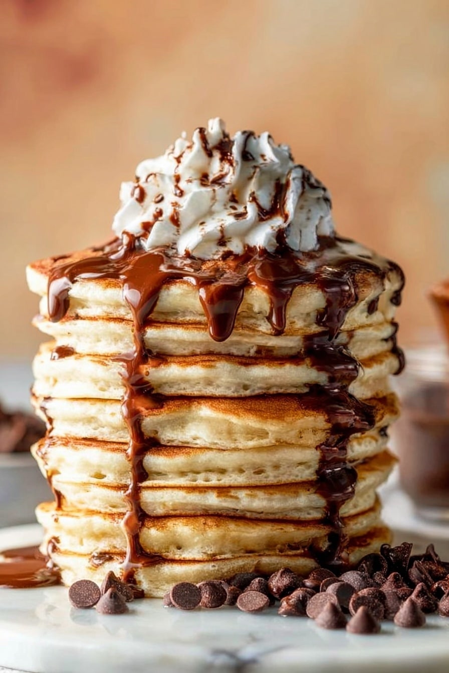 A tall stack of nine thick, golden brown pancakes is shown on a white marbled surface, each pancake fluffy with slightly crisp edges. Chocolate syrup slowly drips down the sides of the stack, creating shiny dark brown streams over the light tan pancakes. A small pile of chocolate chips is scattered around the base of the stack, adding texture and darker brown spots. On top, a swirl of white whipped cream sits high and soft, with more chocolate syrup drizzled over the cream in thin lines. The background is softly blurred with warm tones giving a cozy feel. photo taken with an iphone --ar 2:3 --v 7 - Fluffy Chocolate Chip Pancakes, chocolate chip pancake recipe, easiest pancake recipe, fluffy breakfast ideas, quick breakfast pancakes