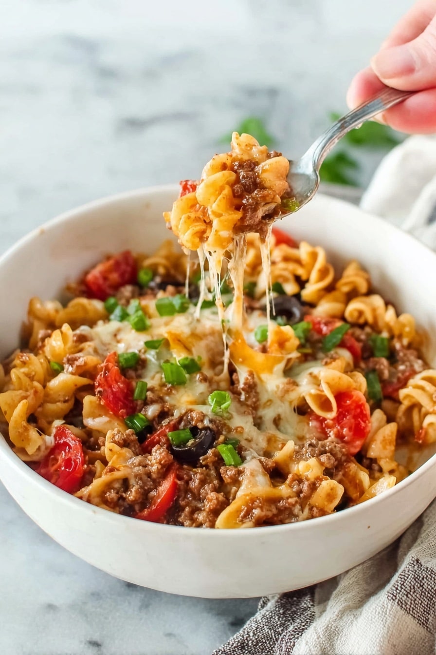 A white bowl filled with a cheesy pasta dish showing three main layers. The bottom layer is melted cheese that stretches as a woman's hand holds a fork lifting the pasta. The middle layer contains curly pasta mixed with cooked ground meat, melted cheese, and small pieces of red tomato. The top layer has sliced black olives and chopped green onions scattered on the pasta. The bowl sits on a white marbled surface with a piece of cloth visible to one side. Photo taken with an iphone --ar 2:3 --v 7 - Cheesy Taco Pasta, easy taco pasta dinner, one-pot cheesy pasta, quick taco pasta recipe, flavorful taco pasta dinner